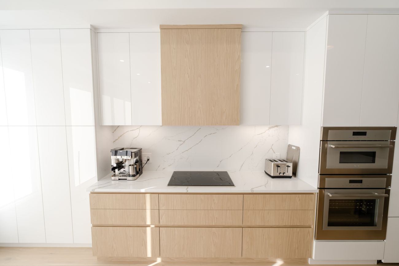 Handleless kitchen run in pale oak with stone splashback